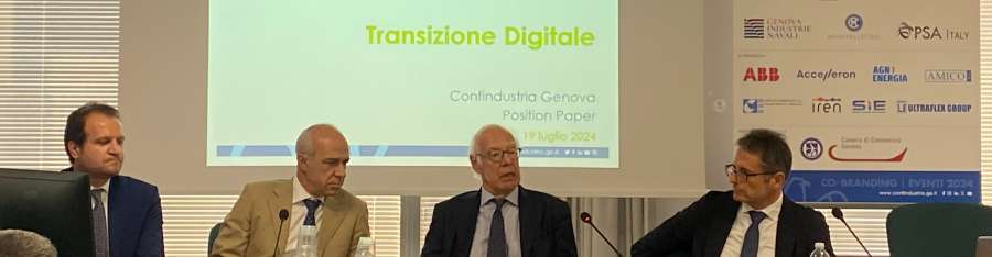 Quattro persone sedute a un tavolo durante un convegno. Schermo con titolo “Transizione Digitale” sullo sfondo.